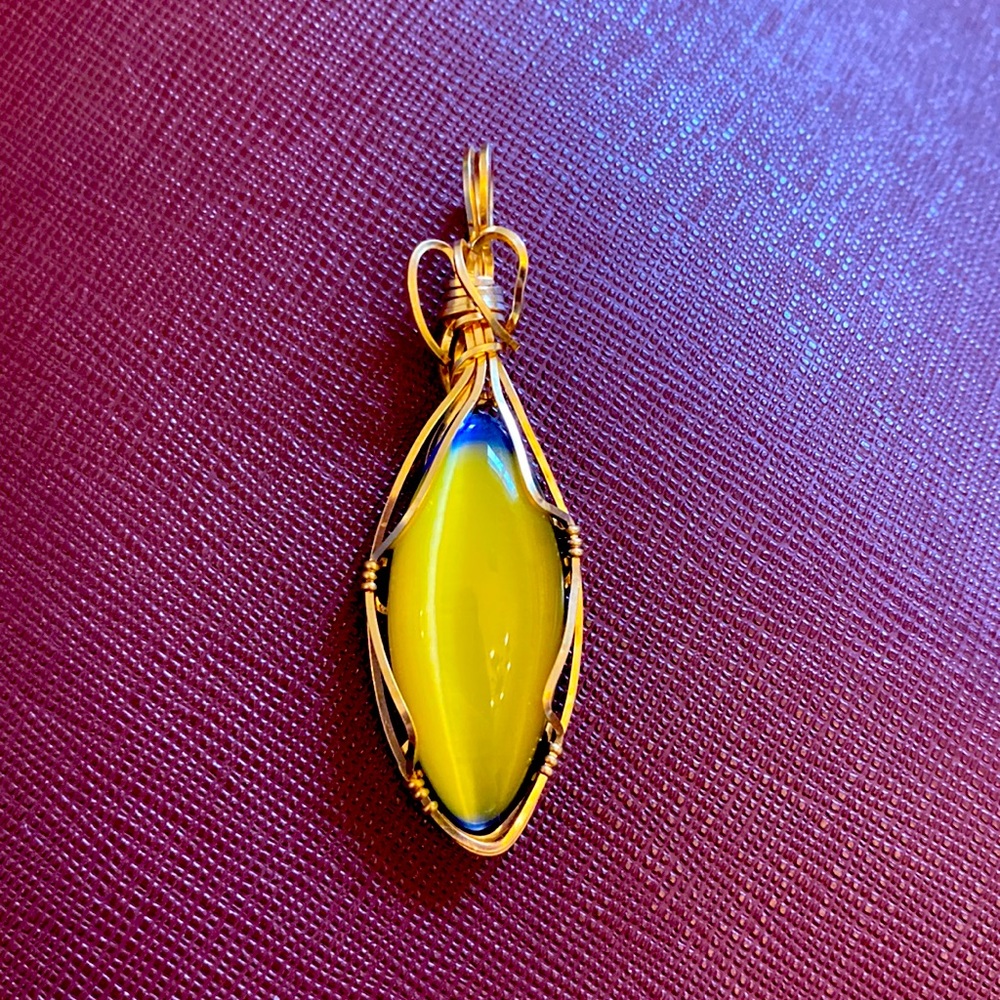 Beautiful large wire wrapped pendant with yellow and blue stone. Gold tone metal